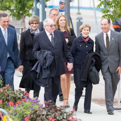Group of people, men and women of mixed age in formal attire, walking outside