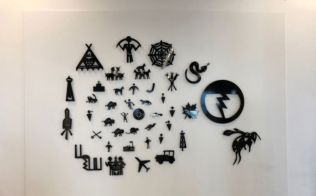 Collection of multiple metal figures of animals, people and structures arranged on a wall in a circular fashion